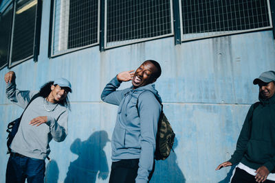 Young friends dancing against wall in city