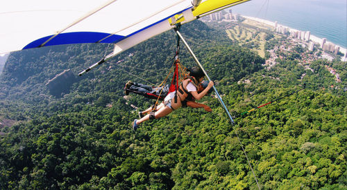 Man and woman hang gliding over mountain