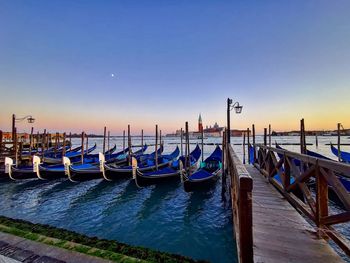 Gondole moored in sea against clear blue sky in venice at sunset 