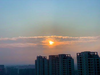 Modern buildings against sky during sunset