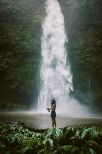 Young woman standing against waterfall