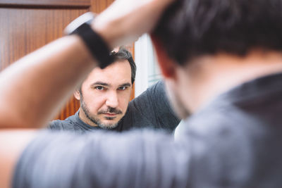 Portrait of young man reflecting in mirror