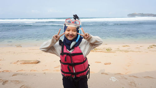 Portrait of woman wearing snorkel standing on beach