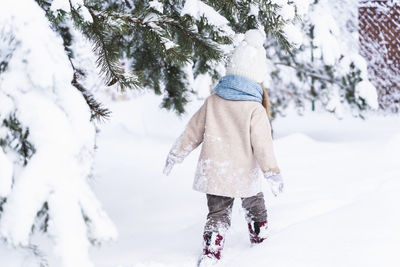 Rear view of woman walking on snow covered land