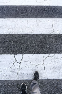 Low section of man standing on zebra crossing