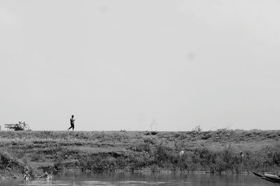 Man walking on field against sky