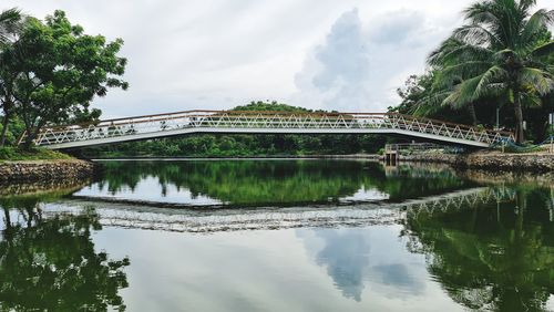 Bridge over river against cloudy sky