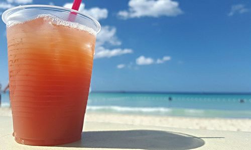 Close-up of drink on beach against sky