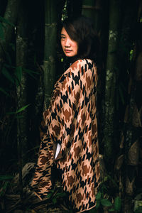 Young woman standing against plants