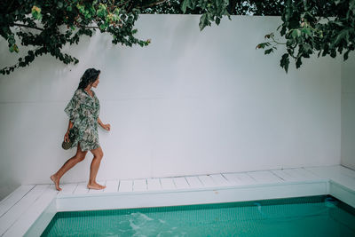 Woman standing by swimming pool against trees