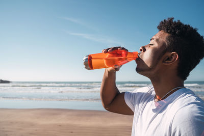 Close-up of man drinking water from beach