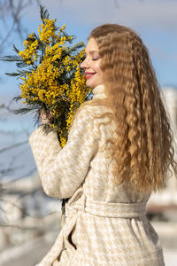 A woman with a bouquet of acacia flowers. the concept of the spring - march 8, easter, women's day.