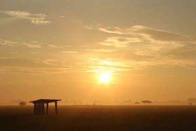 Scenic view of silhouette field against sky during sunset