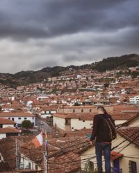 Rear view of a man looking at cityscape against sky