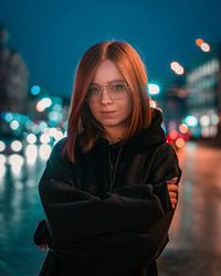 Portrait of woman standing against illuminated light at night