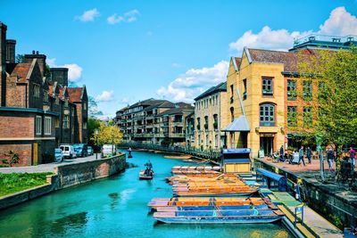 Boats moored on canal amidst buildings against sky