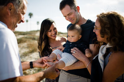 Family smiles as dad holds baby on beach