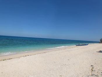 Scenic view of beach against clear blue sky