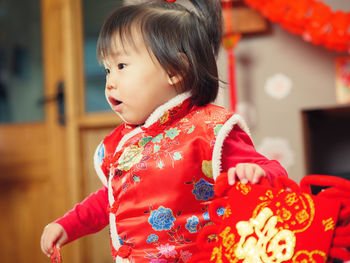 Cute girl in traditional clothing with decoration sitting at home