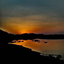 Scenic view of dramatic sky over silhouette trees during sunset