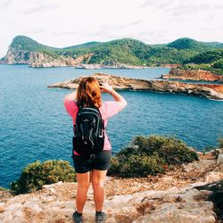 Rear view of woman photographing against sea