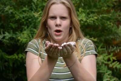 Portrait of teenage girl holding flour against plants