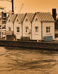 Houses by river against sky in city