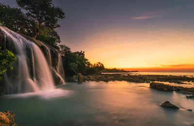 Scenic view of waterfall at sunset