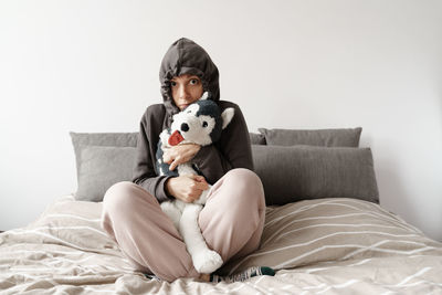 Portrait of cute girl playing with stuffed toy while lying on bed at home