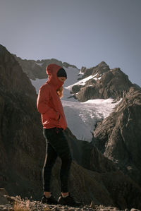Man standing on rock by mountain against sky