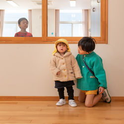 Full length of mother and daughter standing on floor at home