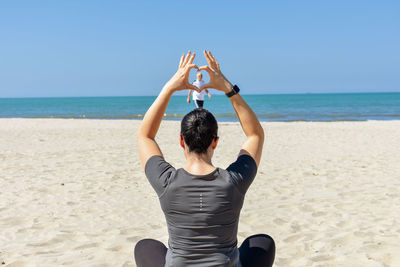 Rear view of woman gesturing against man walking on beach