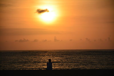 Silhouette woman standing at beach against sky during sunset