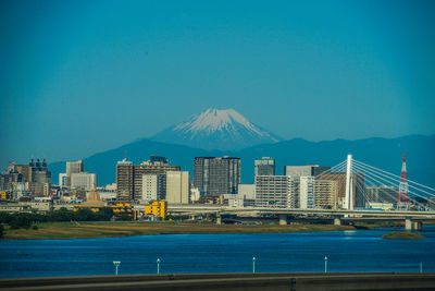 City at waterfront against blue sky