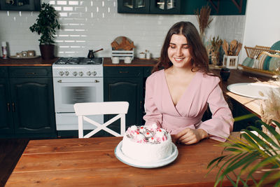 Young woman smiling while standing by table at home