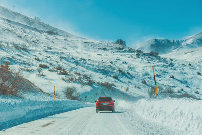 People on snow covered mountain road against sky