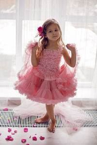 Portrait of a girl in a pink dress and a flower with a rose in her head in the studio