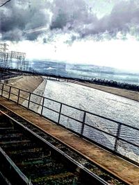 Railroad tracks against cloudy sky