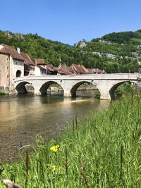 Arch bridge over river against clear sky