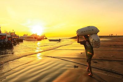 Rear view of man on beach against sky during sunset