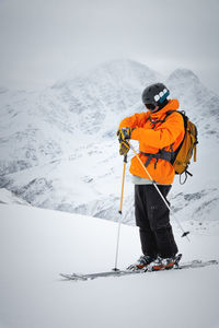 Portrait of a male skier at the top against the backdrop of epic mountains in the clouds.