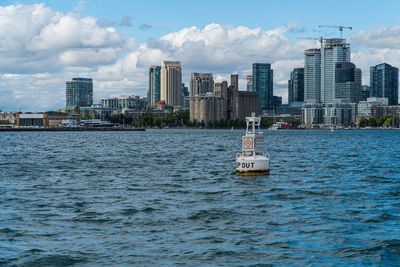 Sea by buildings against sky in city