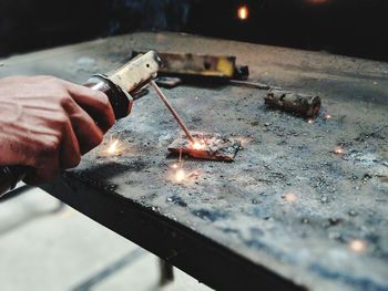 Cropped hand of person welding metal in workshop