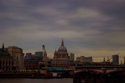 View of city at waterfront against cloudy sky