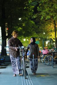 Woman standing on street against trees in city