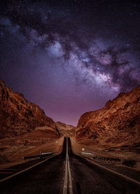 Road amidst field against sky at night