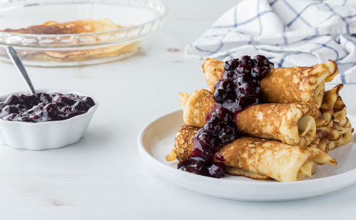 A pile of freshly made crepes topped with sweet blueberry sauce.