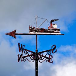 Low angle view of weather vane against sky