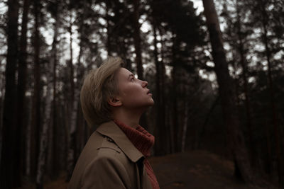 Profile view of woman standing against trees in forest