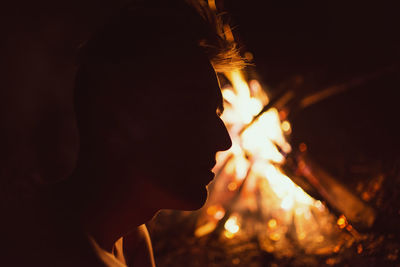 Close-up of man by bonfire on field at night